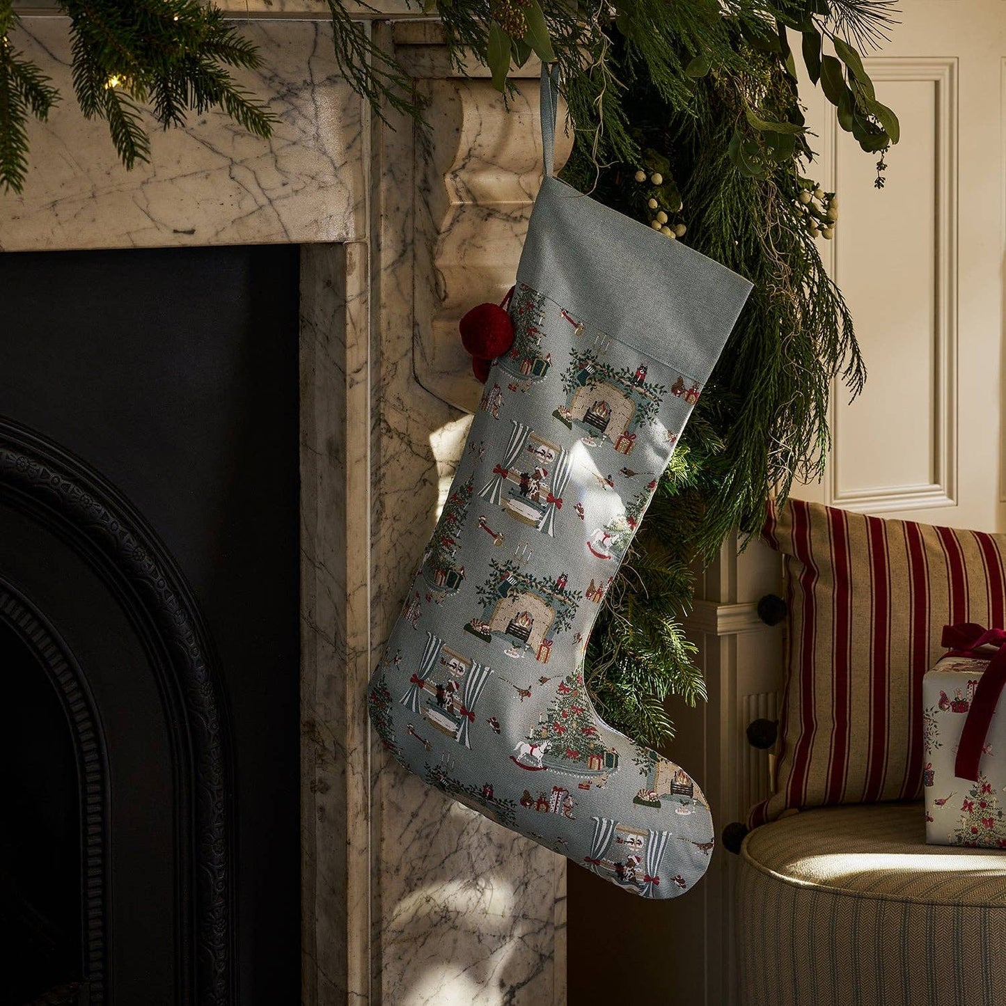 Decorative Christmas stocking hanging by a fireplace with festive decorations.