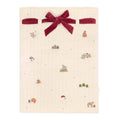 Beige fabric with a red velvet bow and small embroidered designs on a white background