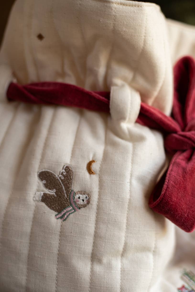Close-up of a white dress with a red ribbon and embroidered design on a blurred background