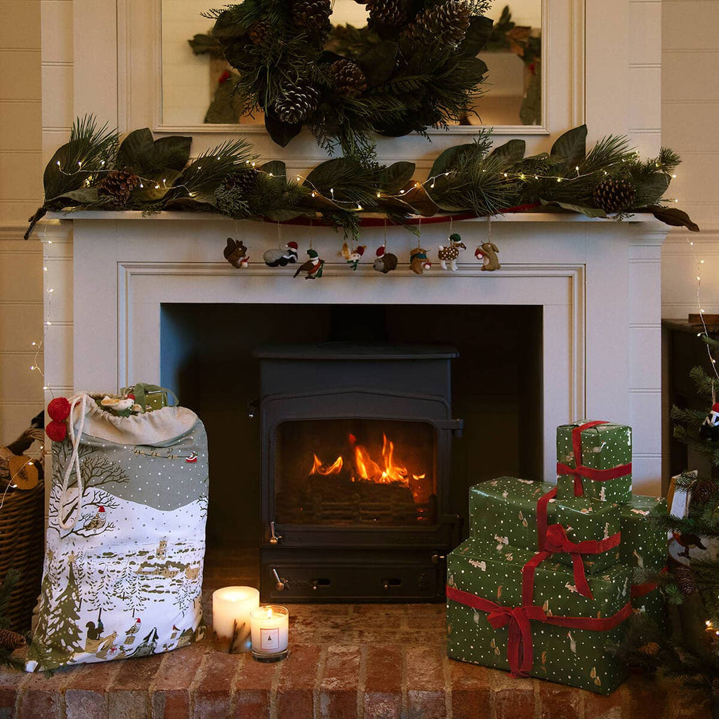 Cozy fireplace with Christmas decorations, including a mantel with greenery and presents.