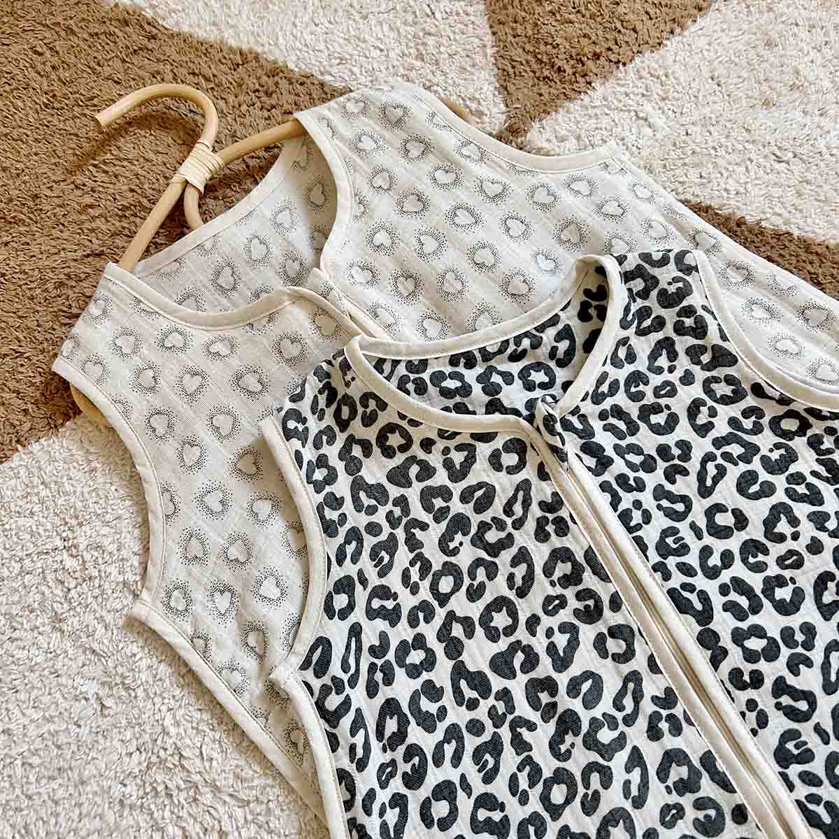 Close-up of the Adele Graou sleeping bag showing its black leopard print, cream edging and sleeveless cotton design beside a neutral patterned version.