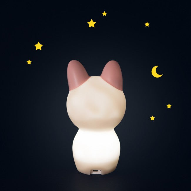 Rear view of the glowing cream cat night light showing its pink ears and charging port at the base against a dark navy background with yellow stars.
