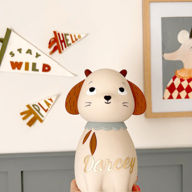 Personalised cream sheep night light displayed beside a woven basket of rolled baby blankets and a soft toy in a nursery.