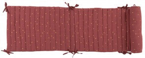 Terracotta After the Rain cot bumper laid flat, showing its quilted panels, small gold leaf details and tie fastenings