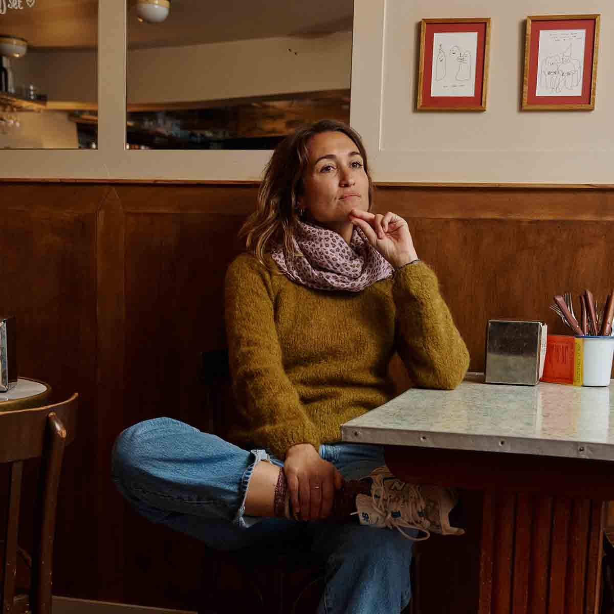 Woman wearing the lilac Mini Leopard muslin scarf as a looped neck scarf with a mustard jumper and blue jeans.