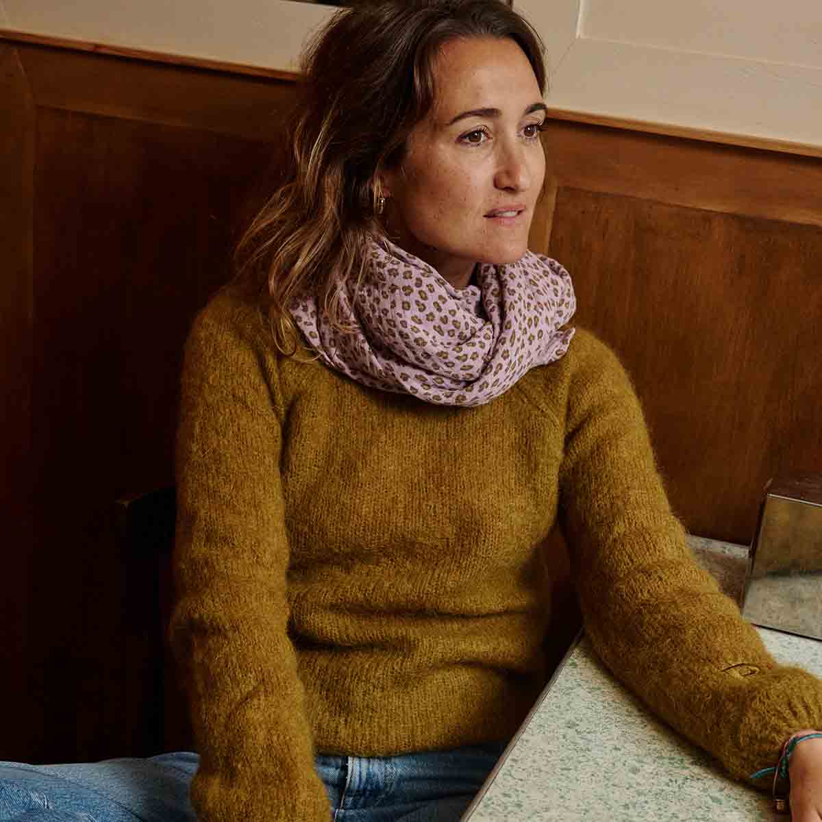 Close-up of a woman wearing the lilac and brown leopard-print muslin scarf around her neck.