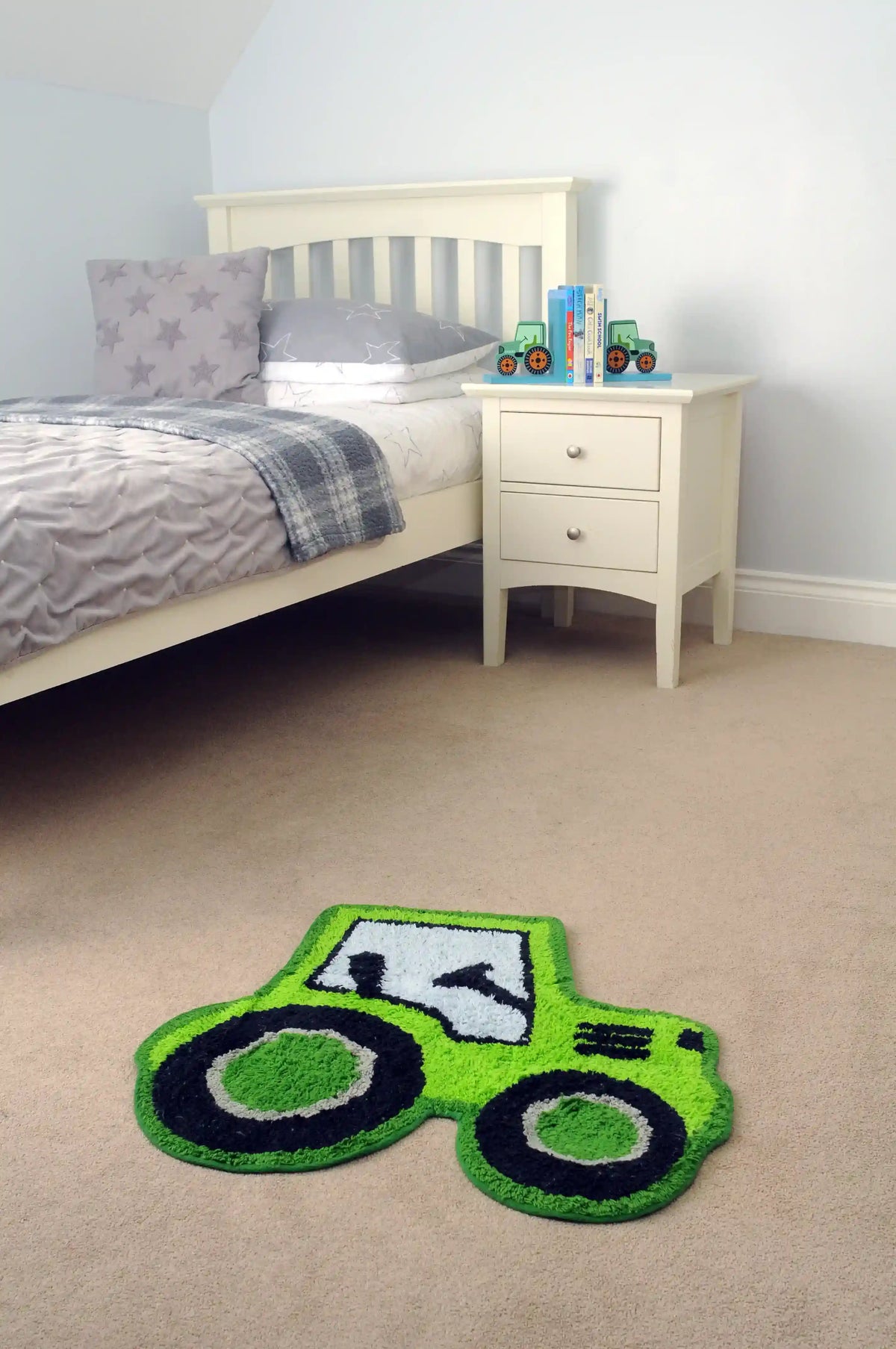Bright green tractor-shaped rug on the floor of a child’s bedroom beside a bed and bedside table