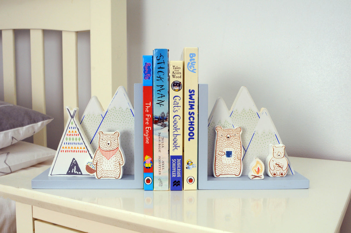 Camping bear bookends holding children’s books on a white bedside table