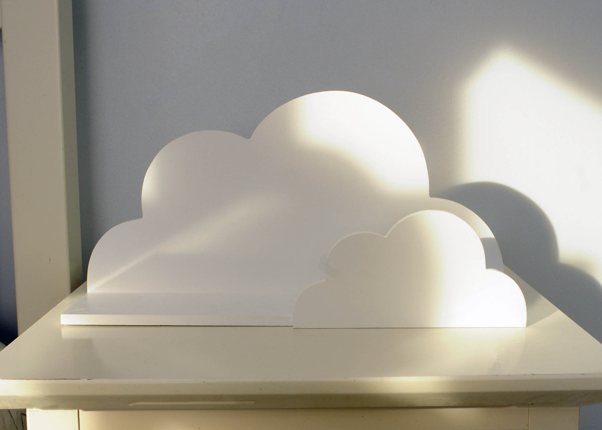 White cloud-shaped wall shelf displayed on a light grey wall with sunlight casting shadows