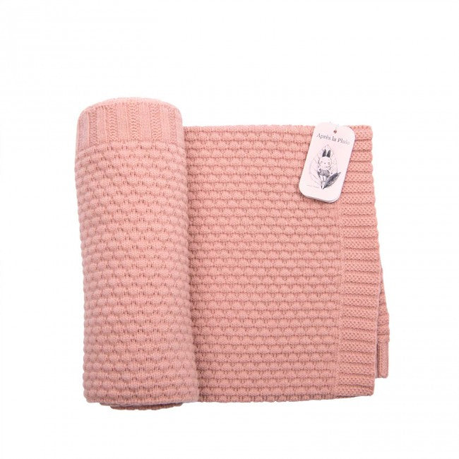 Dusky pink wool blend knitted baby blanket laid flat on a white background, showing its textured knit pattern and ribbed edging