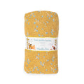 Rolled ochre fitted cot sheet with a delicate blue leaf pattern and Three Little Rabbits packaging on a white background