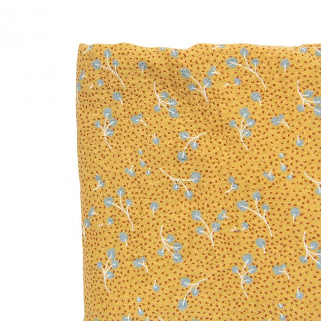 Close-up of an ochre cotton cot sheet with a delicate blue leaf pattern and small dotted details