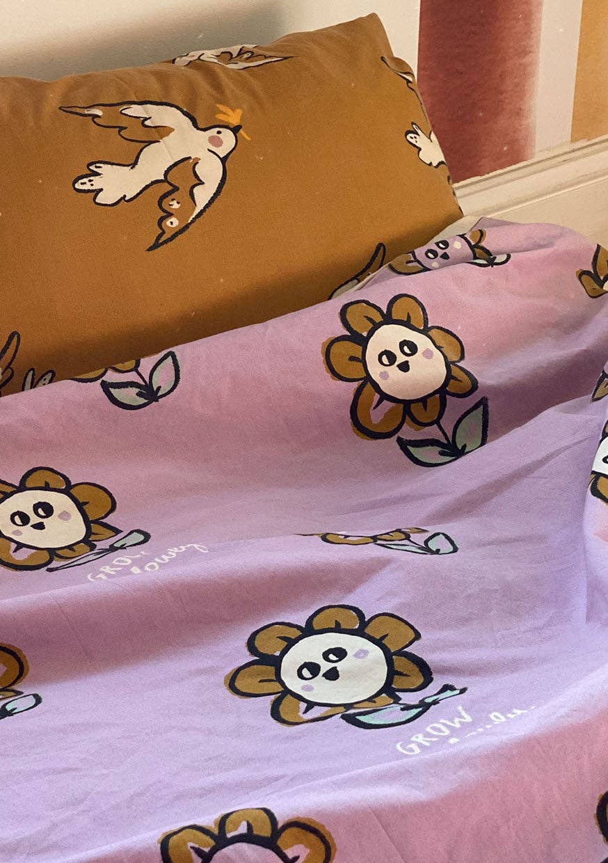 Pink Flower Print duvet cover featuring large yellow flower characters and green leaves, paired with a mustard Bird + Free pillowcase.