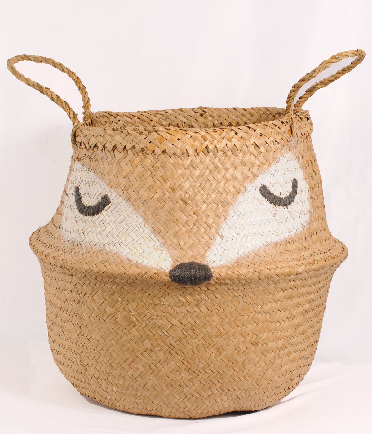 Foxy storage basket woven from natural brown seagrass, featuring a sleepy fox face with closed eyes, white cheeks, a dark nose and two braided handles.