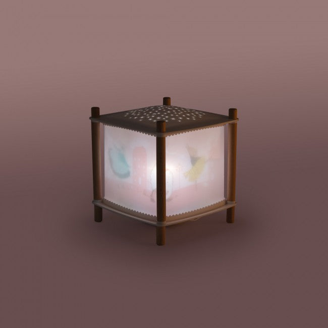 The Little Dance School USB lantern illuminated in a dim setting, showing soft pink panels with ballerina illustrations, a dotted top and light wooden frame.