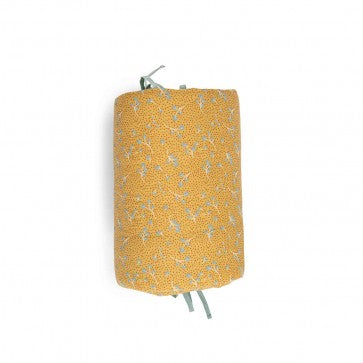 Rolled ochre printed cotton muslin cot bumper with sage-coloured ties on a white background