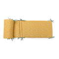 Ochre printed cotton muslin cot bumper with sage-coloured ties displayed on a white background