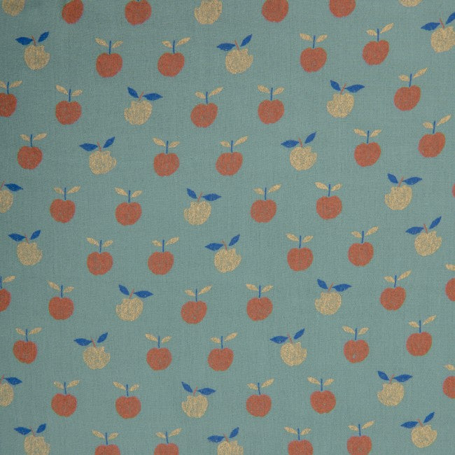 Close-up of the Moulin Roty Pomme des Bois sleeping bag fabric, featuring a blue-green background with repeating rust-orange and yellow apples and small blue leaves.