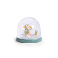 Moulin Roty Three Little Rabbits snow globe with rabbit characters and falling snowflakes on a green base against a white background