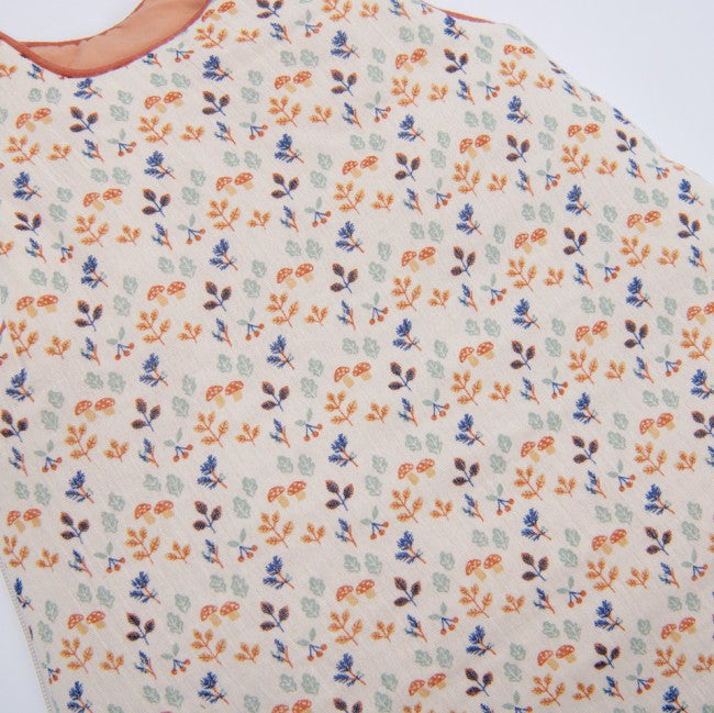 Close-up of the Moulin Roty Woody Apple winter sleeping bag, showing its colourful woodland print and clay-coloured trim around the neckline.