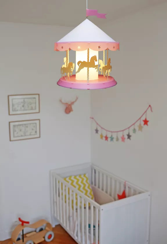 Pink merry-go-round pendant light hanging above a white cot in a colourful nursery