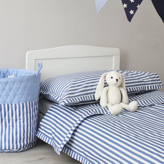Blue and white striped quilted toy storage bag beside a child’s bed with matching striped bedding and a white bunny toy.