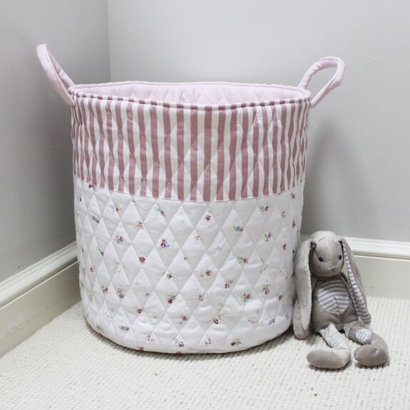 Quilted toy storage bag featuring a pink stripe upper section, a white floral-patterned lower section and two handles, styled beside a grey bunny soft toy.