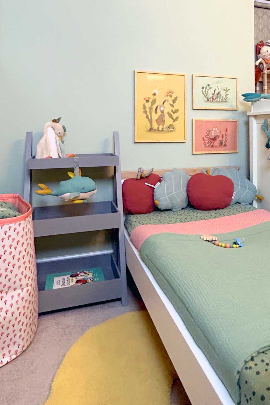 Sage green fitted cot sheet on a child’s bed in a colourful bedroom with matching cushions, wall art and nursery décor