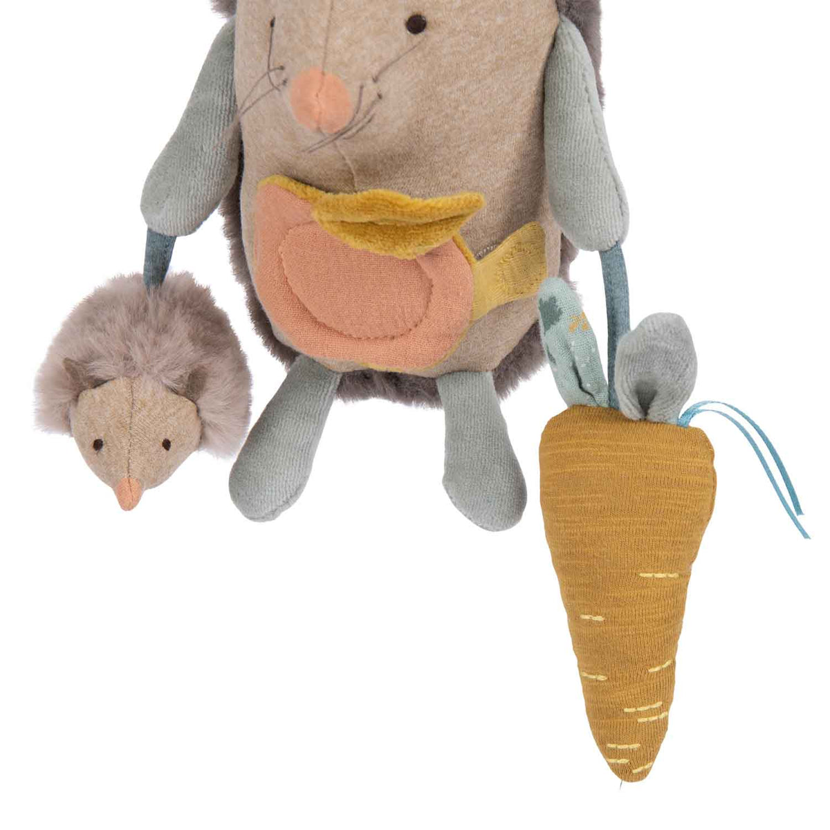 Close-up of the activity hedgehog’s hanging plush companion and mustard-coloured fabric carrot with blue ribbons.