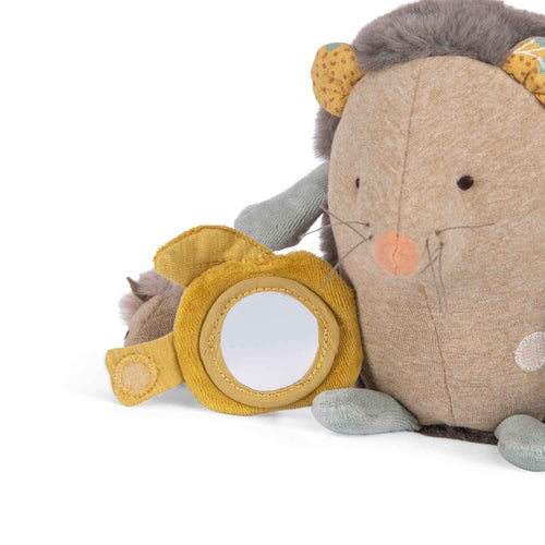 Close-up of the activity hedgehog’s yellow-framed mirror beside its embroidered face and soft fabric details.