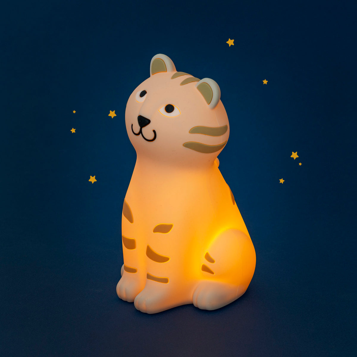 Moulin Roty La Forêt Mawa tiger night light glowing warm orange, with golden-yellow stripes, against a dark blue background decorated with small stars.