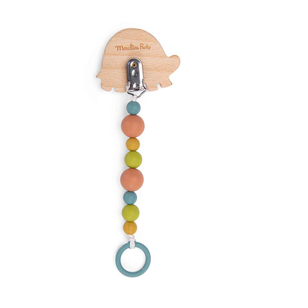 Back view of a wooden turtle soother holder with a metal clip, colourful silicone beads and a blue silicone ring on a white background