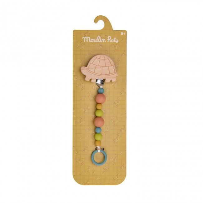 Turtle-shaped wooden soother holder with colourful silicone beads and blue ring displayed on Three Little Rabbits packaging