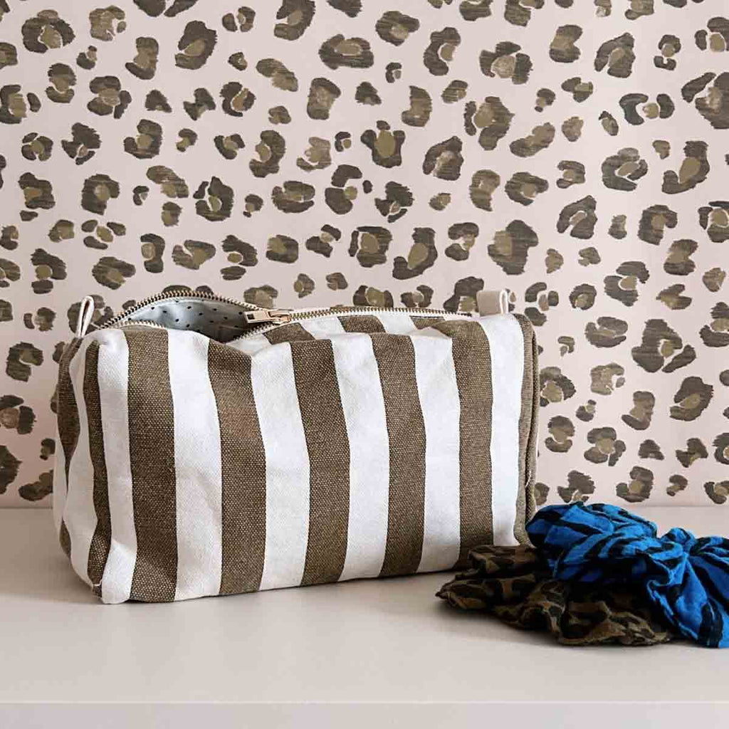 Greek Blue zebra-print scrunchie displayed beside a striped zip pouch and other patterned hair accessories against a neutral animal-print backdrop.