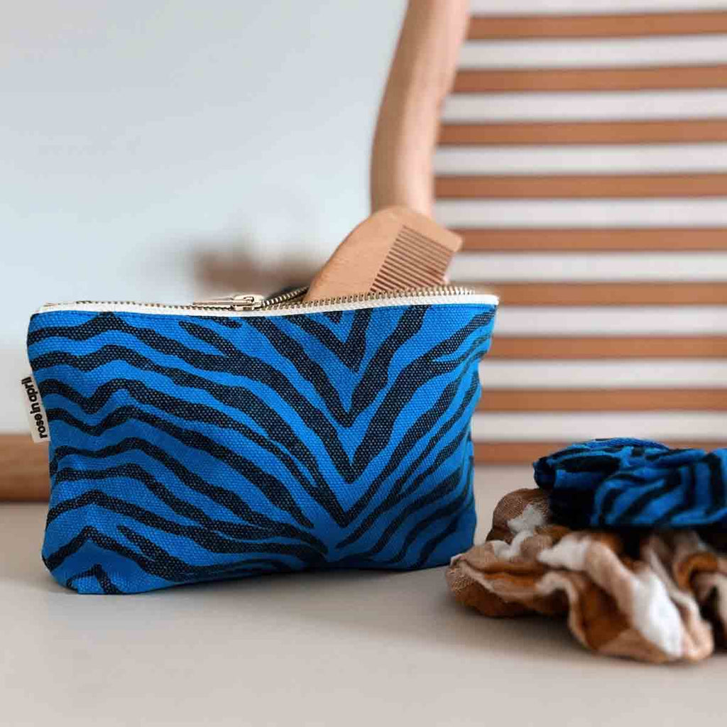 Blue and black zebra-print zip pouch displayed beside a matching Greek Blue scrunchie and other hair accessories.